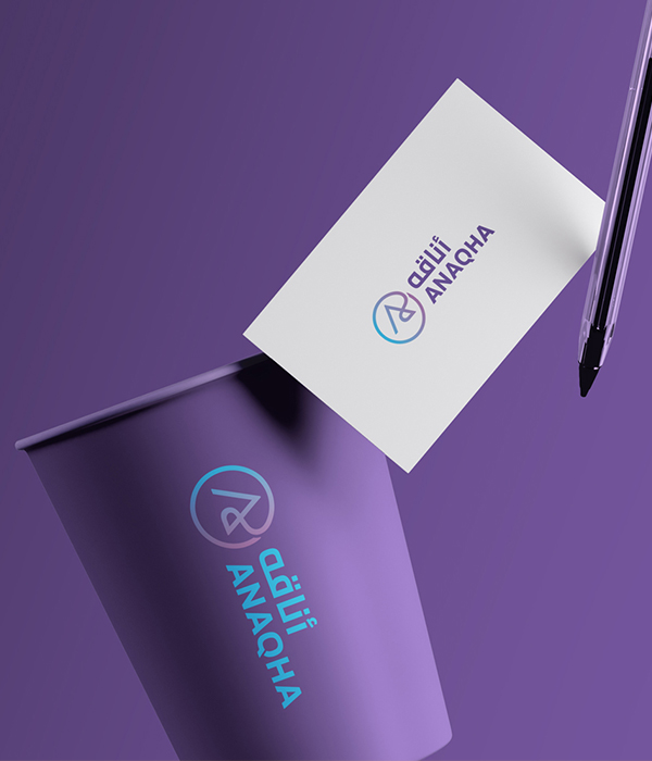 A business card and a purple coffee cup featuring the 
                Anaqha logo in English and Arabic, showcasing brand identity and stationery design. 