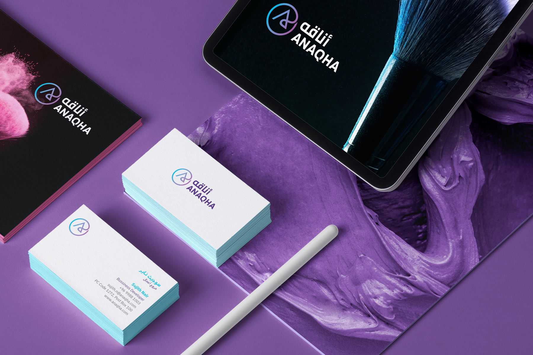 Anaqha cosmetics brand stationery mockup with logo on business cards, brochure, tablet screen, and brush splash visuals in Arabic and English on purple background