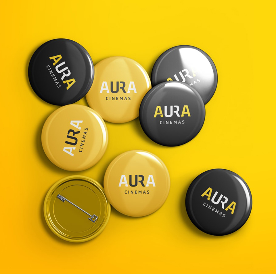 Collection of Aura Cinemas promotional button badges in yellow and black, featuring the Aura logo and 'Cinemas' text, ideal for branding and events in Bengaluru.
