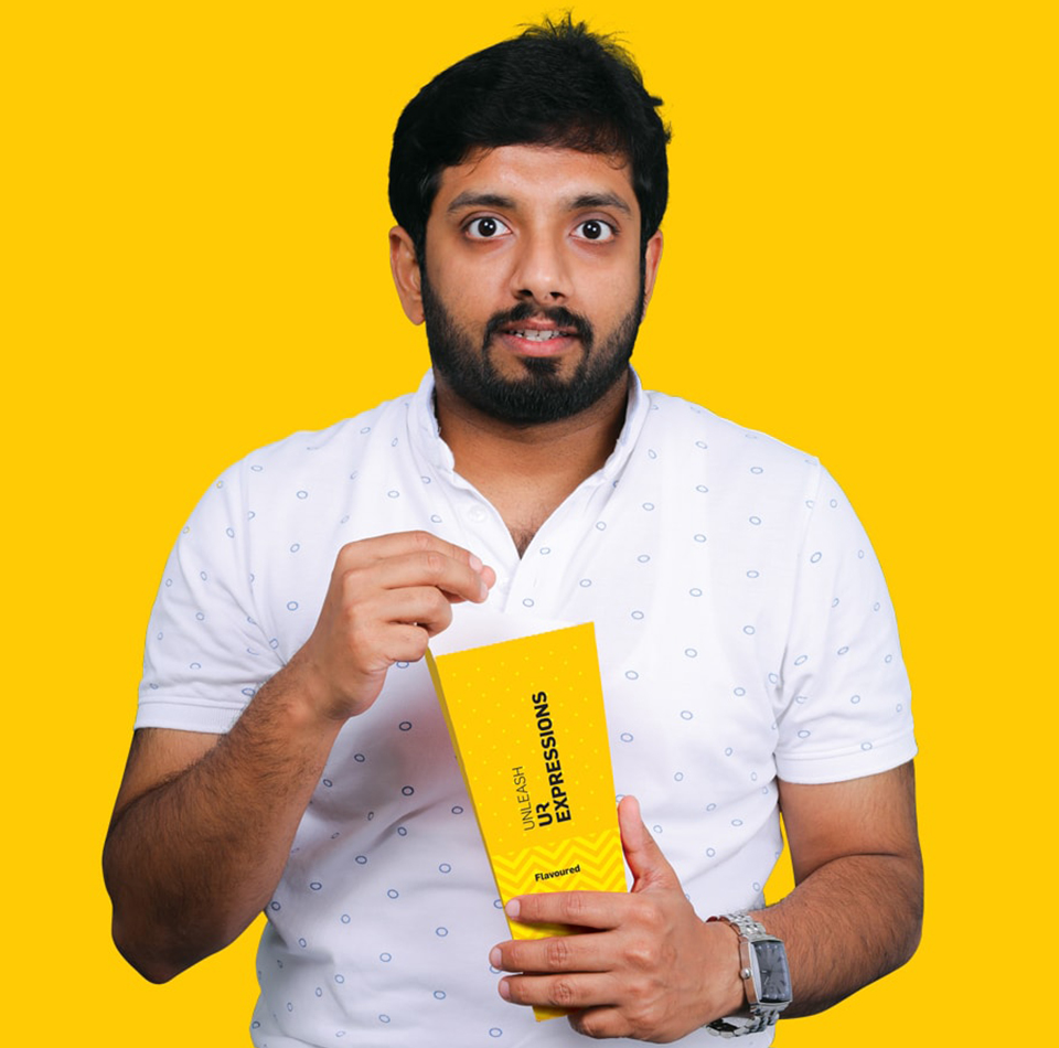 Excited moviegoer in Bengaluru opening a box of flavored popcorn from Aura Cinemas, featuring the brand's tagline.