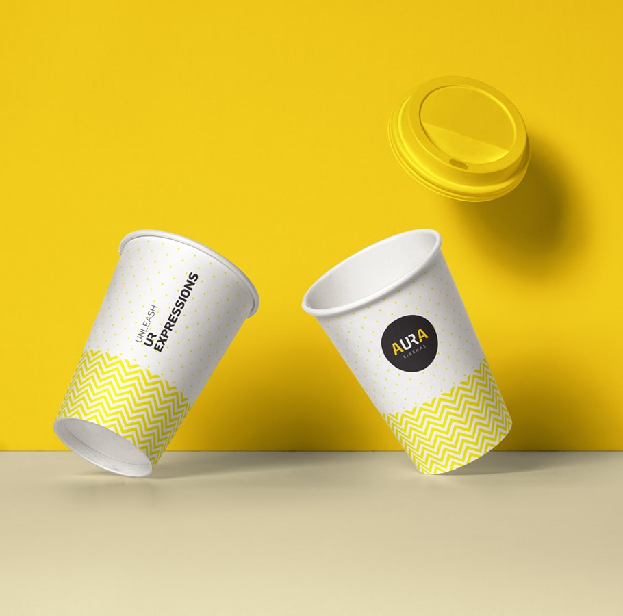 Aura Cinemas branded cups with yellow zigzag patterns and lids, offering a stylish beverage choice for an enjoyable cinema experience