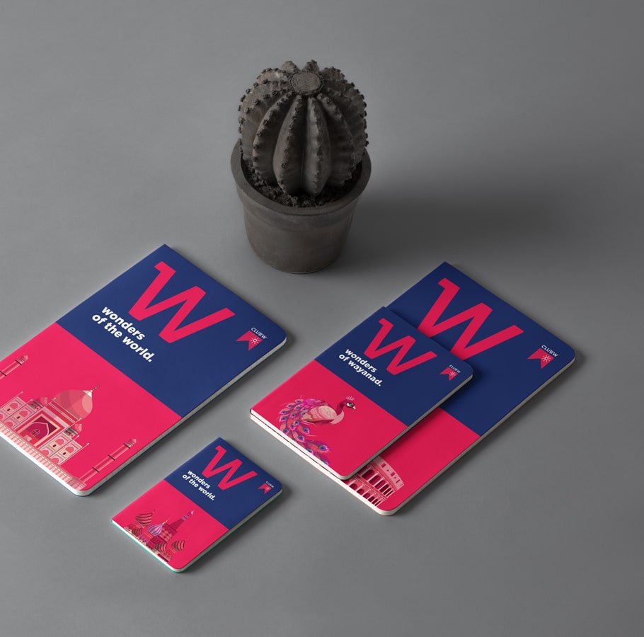Club W Wonders of the World notebook collection with landmark and wildlife illustrations, arranged on gray surface beside cactus plant, showcasing vibrant and modern design