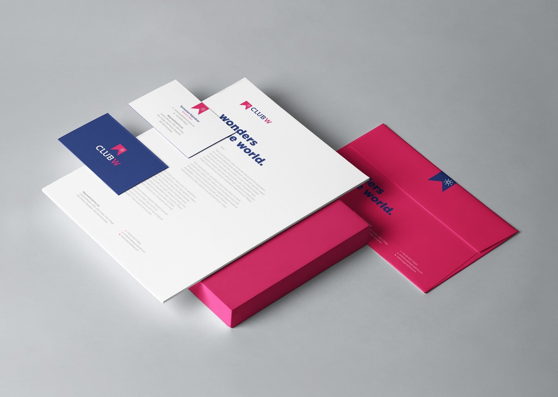 Club W stationery collection featuring branded envelopes, letterhead, and business cards in modern pink and blue color scheme with Wonders of the World tagline