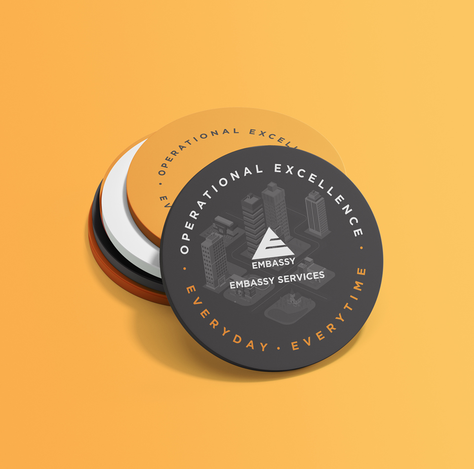 Embassy Services branded coasters with operational excellence slogan on vibrant background