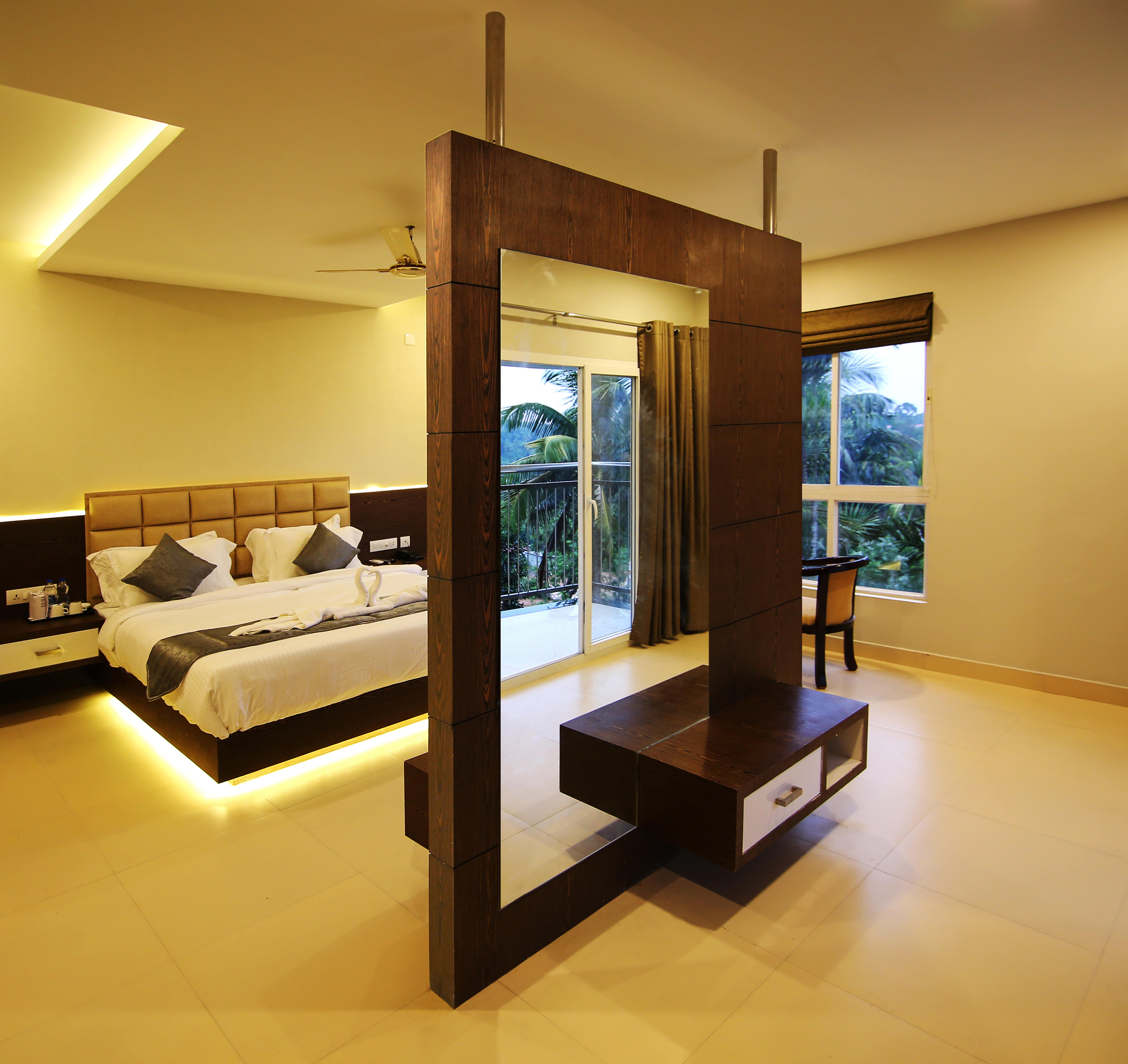 Le SAPPHIRE Hotel luxurious bedroom with modern floating bed, stylish room divider, balcony view, and warm lighting, perfect for a comfortable stay.