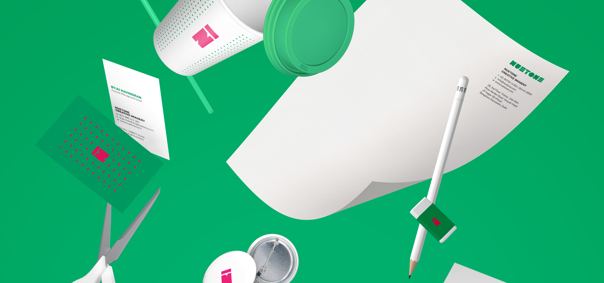 Nuetone creative workspace featuring scissors, a pencil, a coffee cup, business cards, and a pin badge with a pink 'N' logo on a green background, highlighting the brand's design and productivity on the website