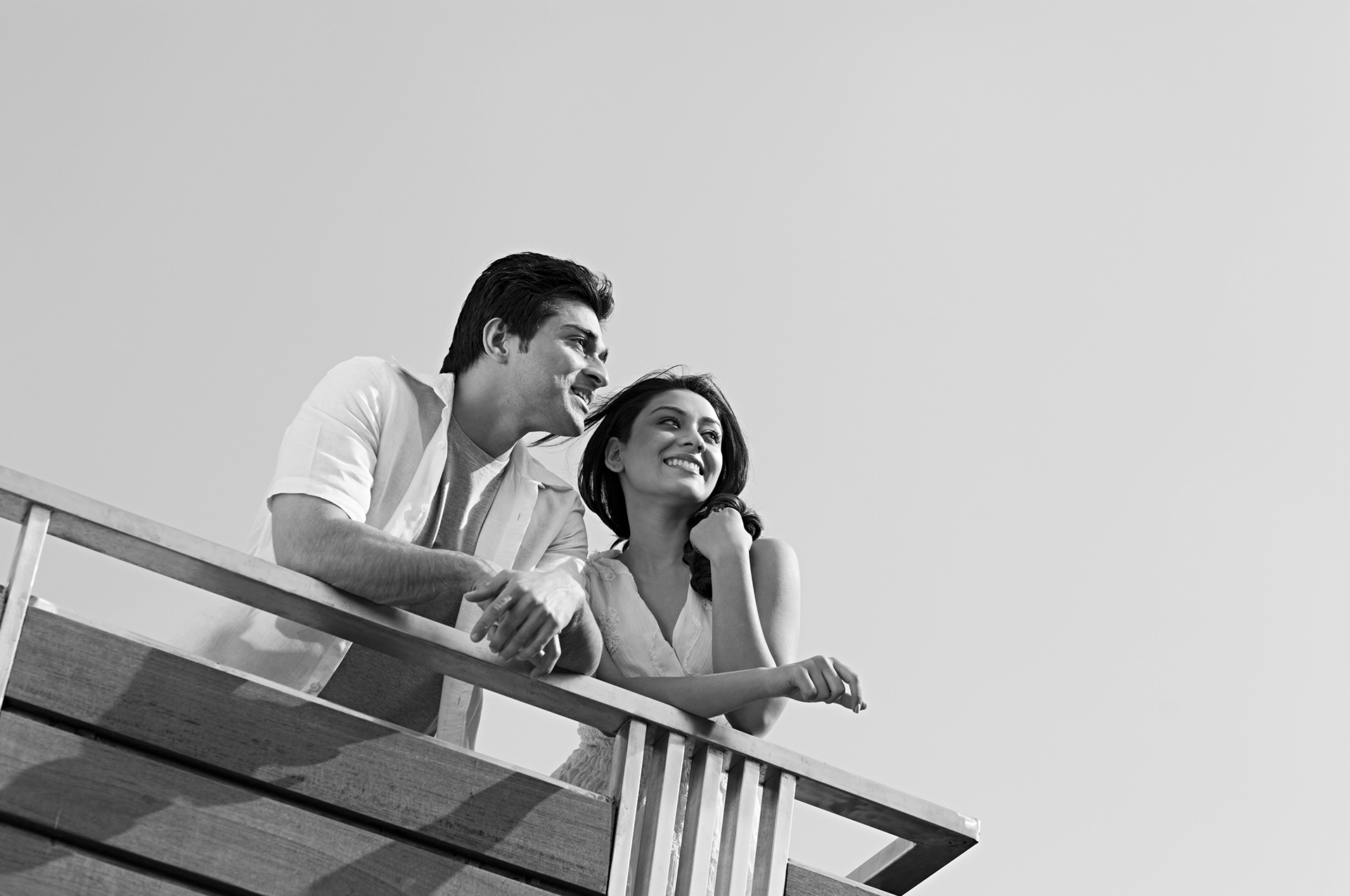 Candid black and white photo of a couple enjoying a serene moment by the railing at Vistara by the Lake resort, capturing peaceful connection and luxury getaway vibe