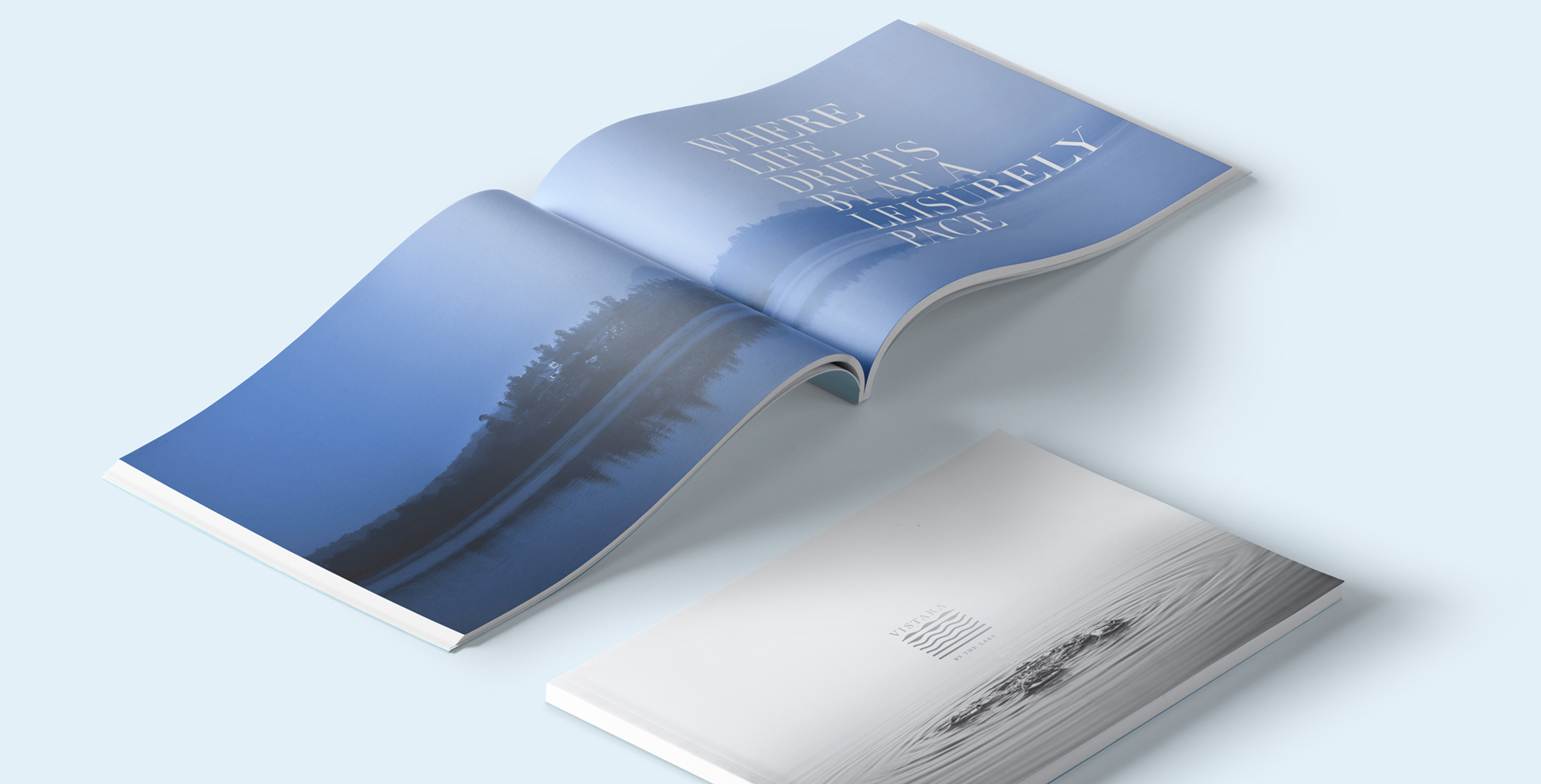 Vistara magazine open to tranquil lake scene with text 'Where life drifts by at a leisurely pace' and closed cover showing rippling water and elegant title