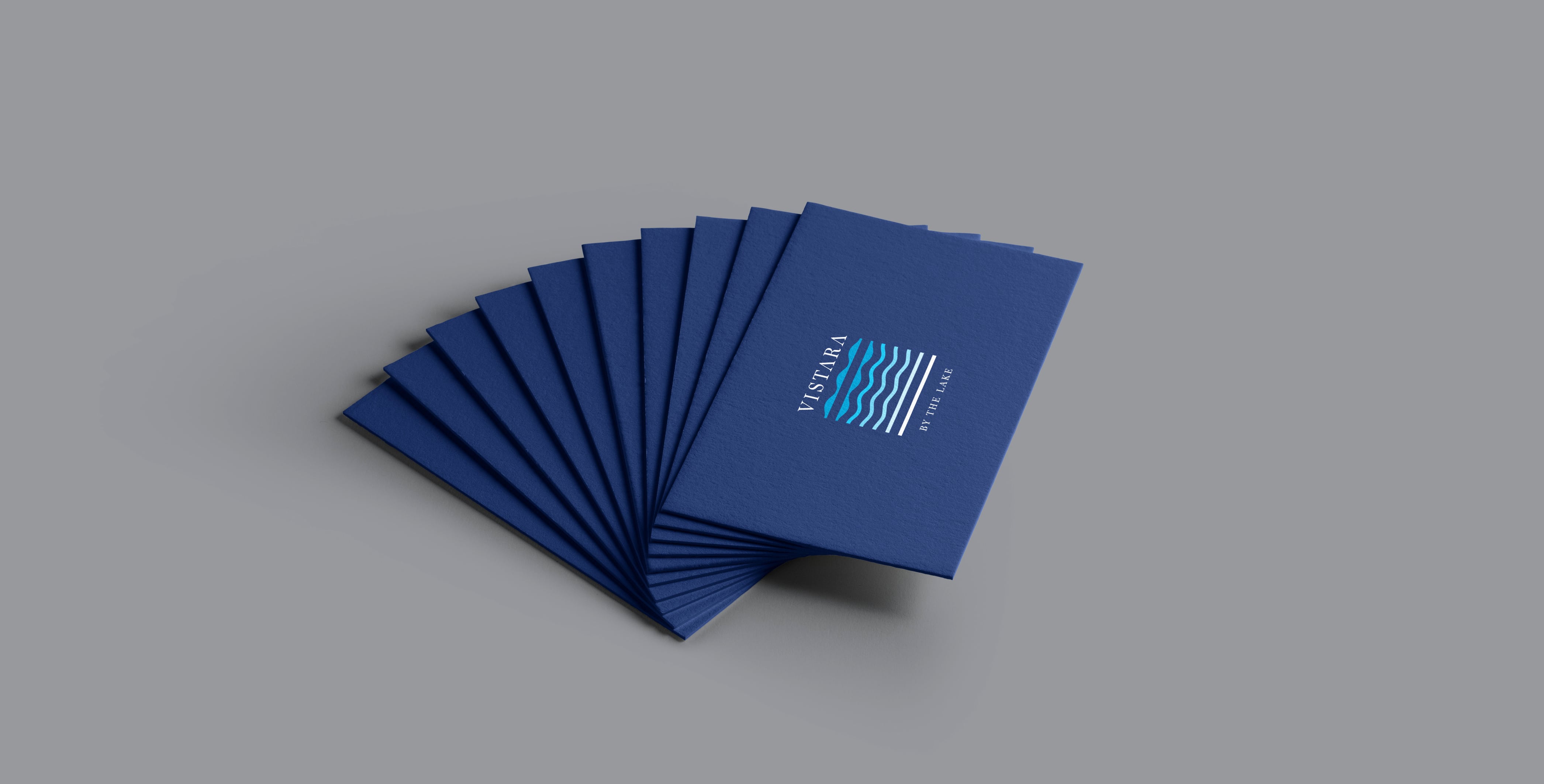 Vistara by the Lake resort blue business cards fanned out on gray background showcasing sophisticated wave-logo branding and luxury hospitality identity